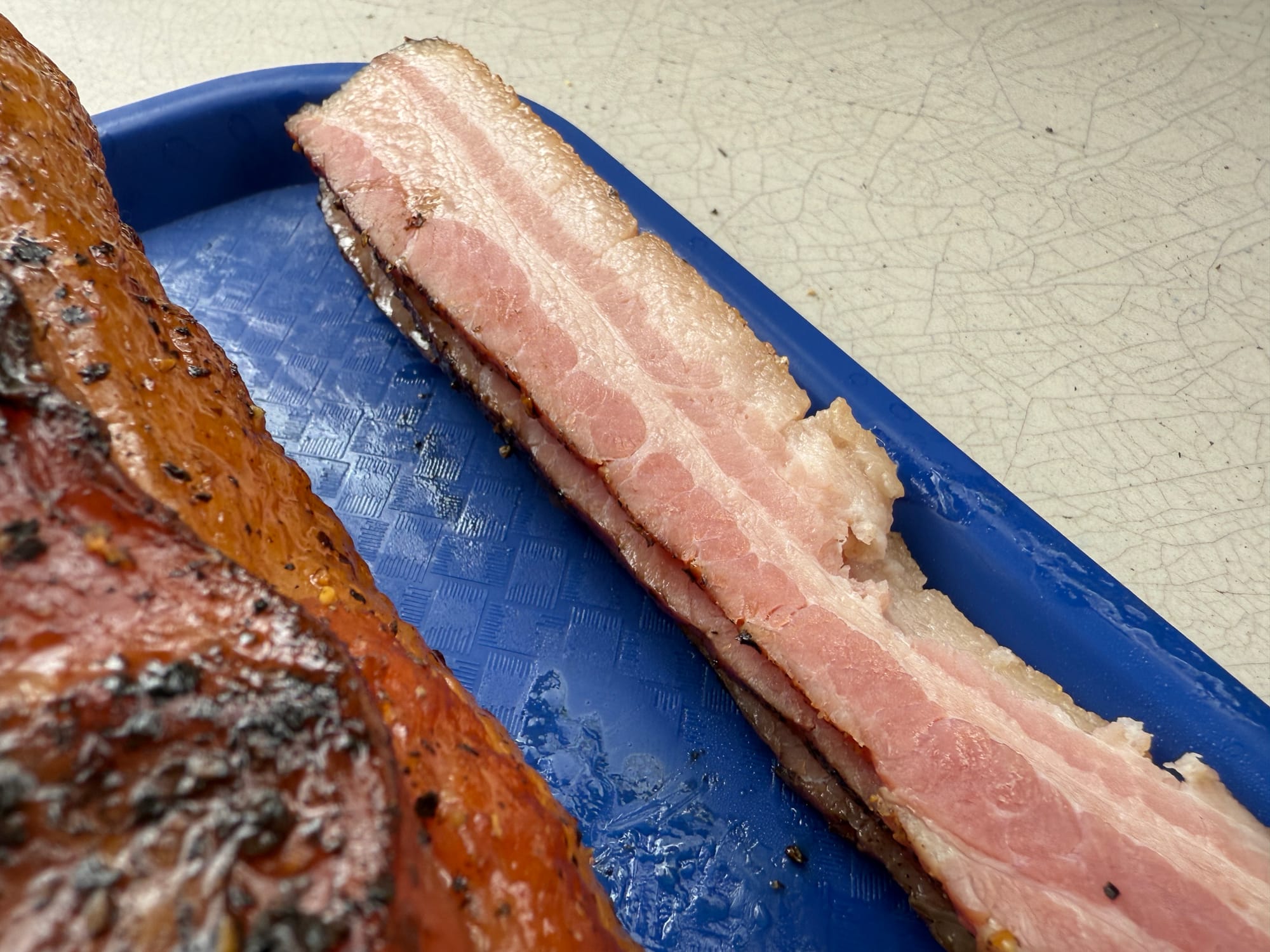 Some slices of bacon next to the pork belly.