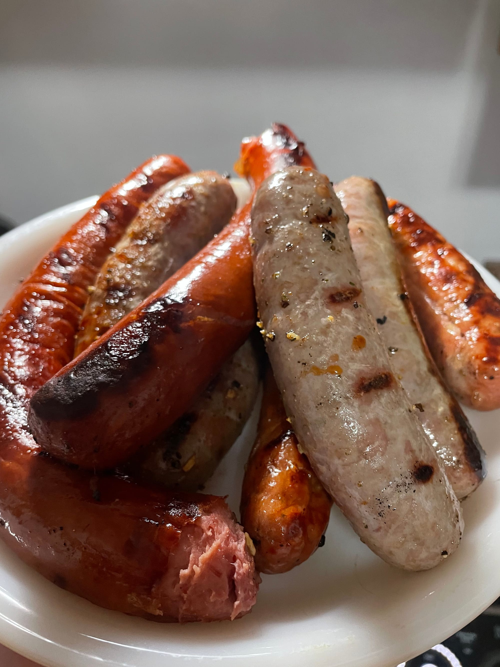 A plate stacked full of different sausages, grilled and seasoned.