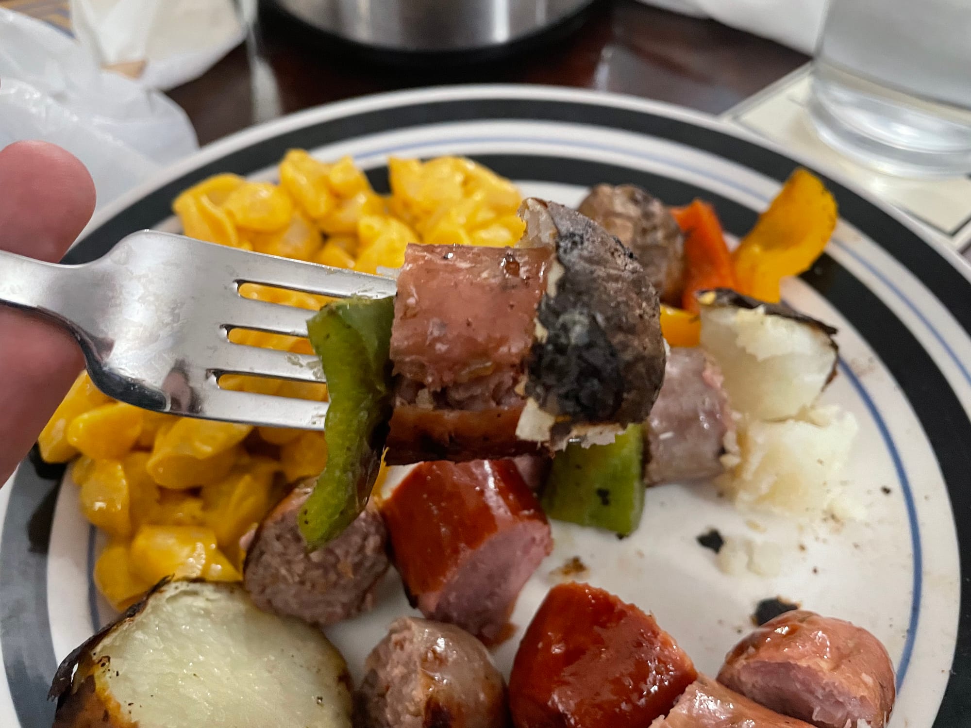 A fork full of sausage, potato, and pepper.