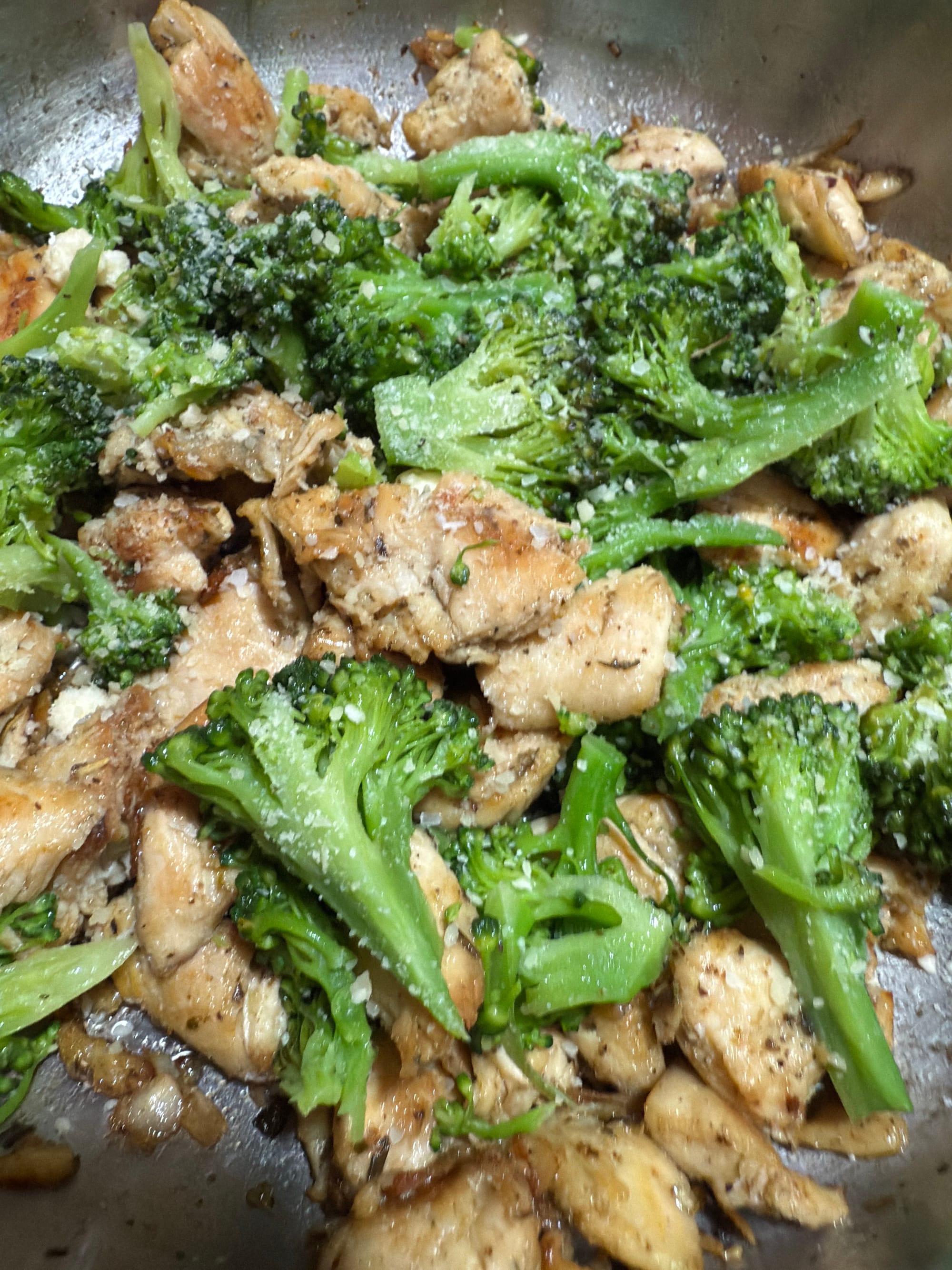 A skillet loaded with broccoli and chicken for alfredo.