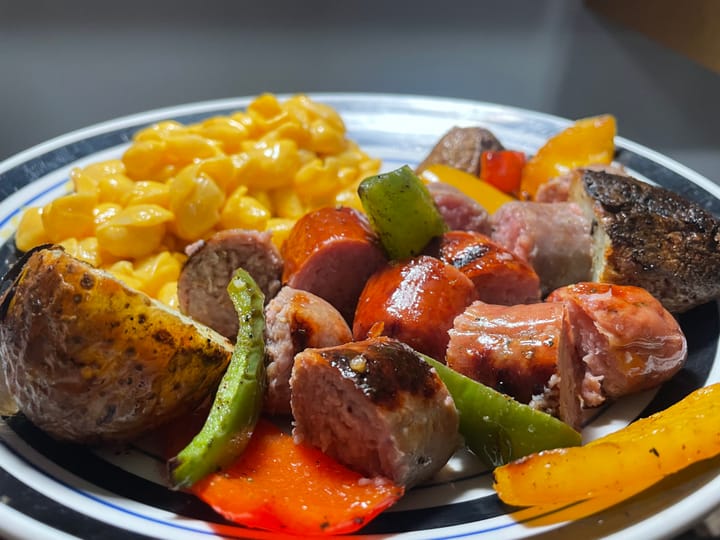 Header image features a plate loaded up with sausages, potatoes, bell peppers, and velveeta shells and cheese.